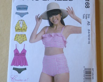 May include: McCall's sewing pattern for a swimsuit with a gingham print. The pattern includes a high-waisted bottom and a ruffled top. The pattern is for sizes 6-8-10-12-14.