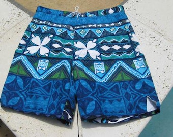 May include: Blue and green patterned swim trunks with a white drawstring. The pattern features geometric shapes and stylized floral designs.