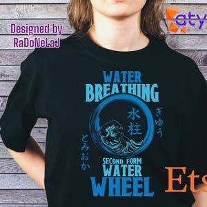 Puede incluir: Camiseta negra con un diseño gráfico azul que presenta las palabras "WATER BREATHING" y "WATER WHEEL". El diseño incluye caracteres japoneses y una ilustración de olas. La camiseta está diseñada por RaDoNeLaJ.