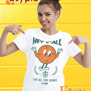 Puede incluir: Camiseta blanca con un personaje de dibujos animados en forma de reloj que lleva un pañuelo rojo y el texto "Hey y'all" encima del personaje. El texto "For all time always Loki" está debajo del personaje.