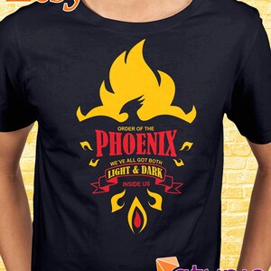 Puede incluir: Una camiseta negra con un gráfico amarillo y rojo de un fénix con el texto "Orden del Fénix Todos tenemos tanto Luz & Oscuridad Dentro de nosotros".