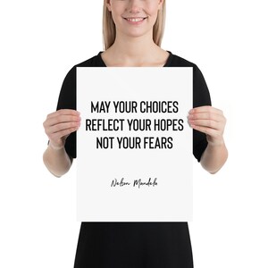 Peut inclure: Une affiche blanche avec du texte noir qui dit "May your choices reflect your hopes not your fears" et "Nelson Mandela" en cursive. L'affiche est tenue par une personne.