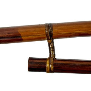 May include: Two wooden sticks connected by a brown leather strap. The sticks are brown and dark brown with a wood grain pattern.