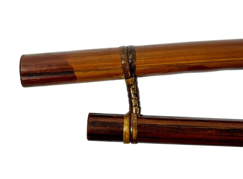 May include: Two wooden sticks connected by a brown leather strap. The sticks are brown and dark brown with a wood grain pattern.
