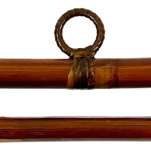 May include: Two brown bamboo rods with a woven brown leather ring at the top. The rods are approximately 1 inch in diameter.