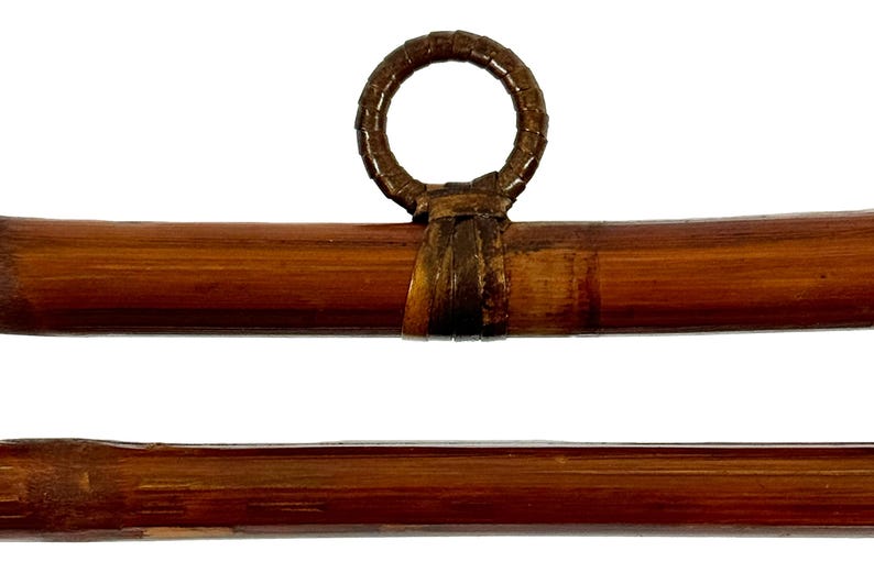 May include: Two brown bamboo rods with a woven brown leather ring at the top. The rods are approximately 1 inch in diameter.