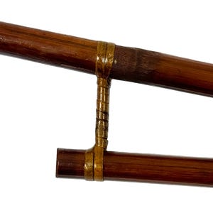 May include: A pair of brown bamboo sticks connected by a gold metal band. The sticks are used for a traditional Japanese game.