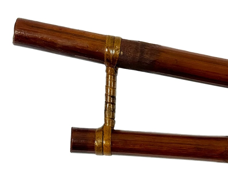 May include: A pair of brown bamboo sticks connected by a gold metal band. The sticks are used for a traditional Japanese game.