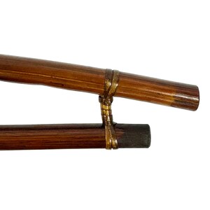 May include: Two brown wooden sticks connected by a gold-colored band. The sticks are about 12 inches long and have a smooth, polished finish.