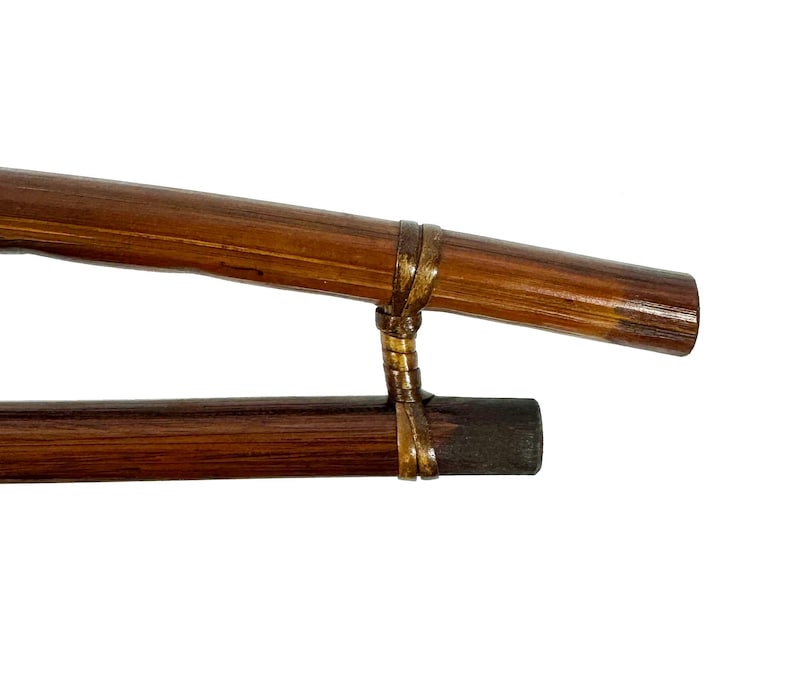 May include: Two brown wooden sticks connected by a gold-colored band. The sticks are about 12 inches long and have a smooth, polished finish.