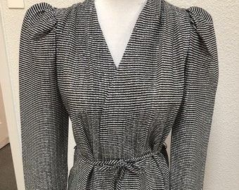 May include: A black and white striped long-sleeved blouse with a V-neck and a tie at the waist.