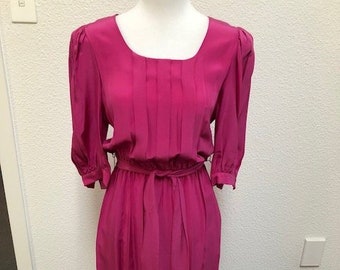 May include: A magenta dress with a square neckline, 3/4 sleeves, and a pleated bodice. The dress has a sash tie at the waist.