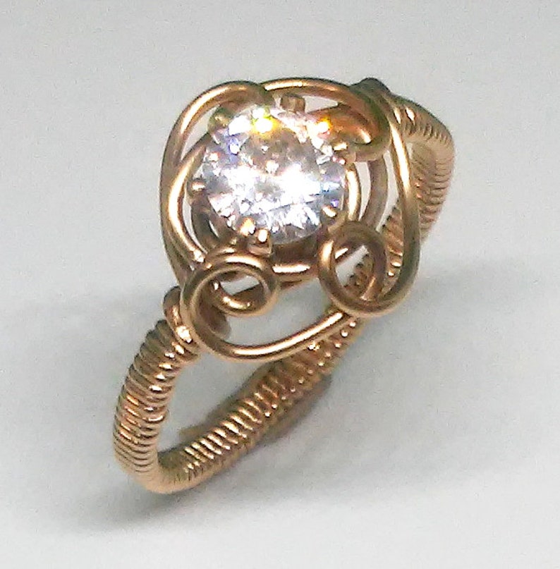 size 10 A wiresculpted ring of 14K gf wire with cubic zirconia stone set in a sculpted small flower with a wrapped shank