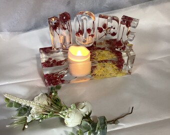 Resin Tea light Holder filled with dried flowers and has letters that say”HOPE”.battery operated