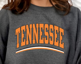 May include: A gray sweatshirt with an orange arch design that says "TENNESSEE" in bold, white outlined letters.