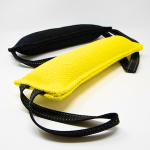 May include: Two dog training bite toys, one yellow and one black, with black straps.