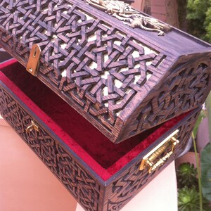 May include: A wooden treasure chest with intricate carvings and a red velvet lining. The chest has two brass clasps and is open to reveal the interior.