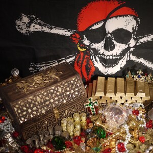 May include: A wooden treasure chest with intricate carvings sits on a table covered in gold coins, jewels, and other pirate-themed treasures. A pirate skull and crossbones flag hangs in the background.