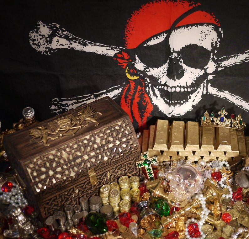 May include: A wooden treasure chest with intricate carvings sits on a table covered in gold coins, jewels, and other pirate-themed treasures. A pirate skull and crossbones flag hangs in the background.