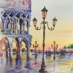 Puede incluir: Pintura acuarela de una escena callejera en Venecia, Italia. La pintura presenta un gran edificio con puertas arqueadas y una farola con m&uacute;ltiples luces. La escena est&aacute; ba&ntilde;ada por una luz c&aacute;lida y dorada.
