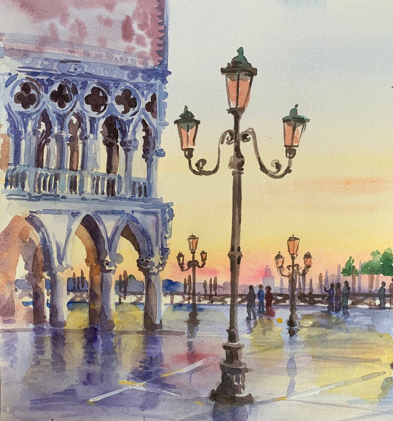 Puede incluir: Pintura acuarela de una escena callejera en Venecia, Italia. La pintura presenta un gran edificio con puertas arqueadas y una farola con m&uacute;ltiples luces. La escena est&aacute; ba&ntilde;ada por una luz c&aacute;lida y dorada.