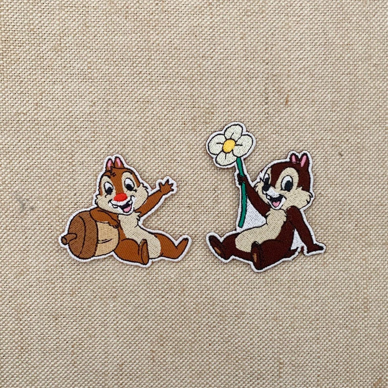 May include: Two embroidered iron-on patches featuring Chip from Disney's Chip 'n Dale. One patch shows Chip holding an acorn, the other shows Chip holding a white flower.