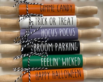 May include: Six wooden rolling pins with Halloween themed sayings. The sayings are "Gimme Candy", "Trick or Treat", "Hocus Pocus", "Broom Parking", "Feelin' Wicked", and "Happy Halloween".