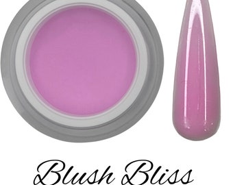 Könnte beinhalten: Ein Glas mit hellrosa Acrylpulver und eine kleine Probe des Pulvers auf einem Nagelspitzen. Das Glas und die Nagelspitze befinden sich auf einem weißen Hintergrund. Der Text "Blush Bliss" steht unter dem Bild.