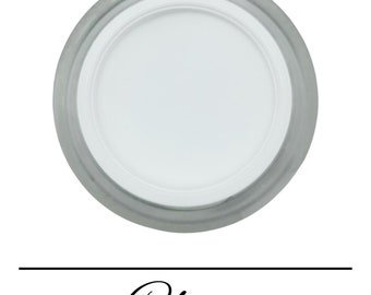 Könnte beinhalten: Ein rundes, transparentes Glas mit einem weißen Deckel. Das Glas ist mit einer weißen Substanz gefüllt. Das Wort "Klar" steht unter dem Glas.