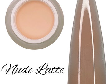 Könnte beinhalten: Ein kleines Glas mit nude-lattefarbenem Nagel-Dip-Pulver. Das Pulver befindet sich in einem durchsichtigen Glas mit weißem Deckel. Das Glas steht auf einem weißen Hintergrund. Das Pulver ist auch auf einem Nagel-Tip zu sehen, der sich ebenfalls auf einem weißen Hintergrund befindet. Der Nagel-Tip ist hellbraun.