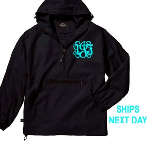 May include: Black hooded pullover jacket with a zipper closure and a turquoise monogram on the front. The jacket has a kangaroo pocket and elastic cuffs.