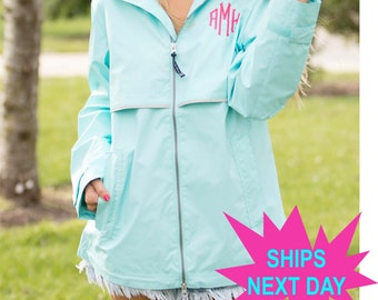 May include: A light blue hooded rain jacket with a white zipper and a reflective strip. The jacket has a monogrammed "AMH" on the left chest.