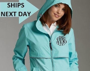 May include: A light blue hooded jacket with a zipper closure and a monogrammed design. The jacket has two pockets and a reflective strip on the front.