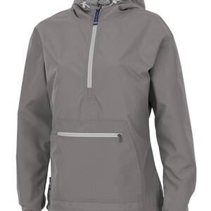 May include: A grey anorak jacket with a hood and a half-zip. The jacket has a front pocket with a zip and elasticated cuffs and hem. The hood's interior lining is a lighter grey colour. A practical outerwear item.