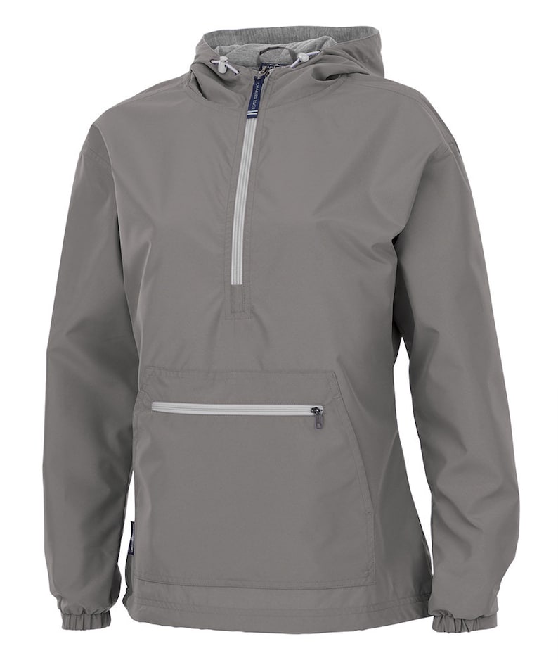 May include: A grey anorak jacket with a hood and a half-zip. The jacket has a front pocket with a zip and elasticated cuffs and hem. The hood's interior lining is a lighter grey colour. A practical outerwear item.