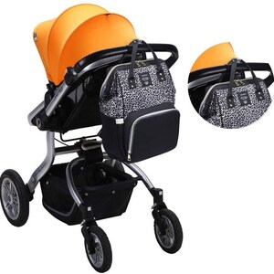 May include: A black and white leopard print diaper bag with gold accents is attached to a silver stroller with an orange canopy. The stroller has a black basket underneath.