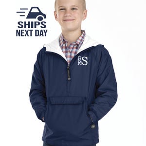 May include: A navy blue youth-sized pullover jacket with a white zipper and a white pocket. The jacket has a white hood and a white embroidered logo that says "BRS".