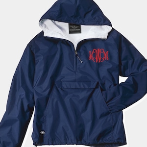 May include: A navy blue hooded windbreaker with a white lining and a red monogram on the front. The jacket has a zipper closure and a kangaroo pocket.