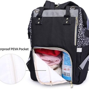May include: A black and grey backpack with a leopard print detail. The backpack has a large zippered pocket on the front and a smaller zippered pocket on the side. The backpack is open and you can see the inside of the bag, which is lined with a white fabric. The backpack has a waterproof PEVA pocket.