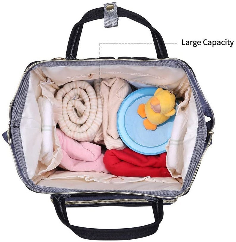 May include: A gray and black diaper bag with a large capacity. The bag is open and filled with various baby items, including a rolled up blanket, a baby toy, and a container of baby formula.