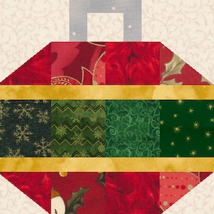 May include: A patchwork Christmas bauble with a festive design. The bauble features a red and green colour scheme with gold accents. The design includes various patterns, such as snowflakes, poinsettias, and holly leaves. The bauble has a light beige background.