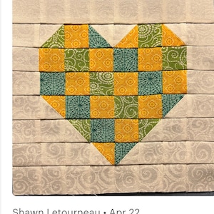 May include: A heart-shaped patchwork quilt block with a pattern of yellow and green squares. The block is surrounded by a border of a light beige fabric with a subtle pattern.