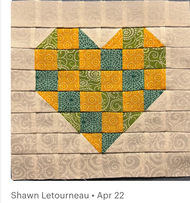 May include: A heart-shaped patchwork quilt block with a pattern of yellow and green squares. The block is surrounded by a border of a light beige fabric with a subtle pattern.