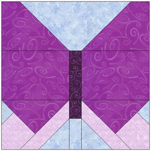 Pode incluir: Um bloco de colcha de borboleta roxo e azul com um design de espiral. A borboleta é composta por 10 peças de tecido diferentes.