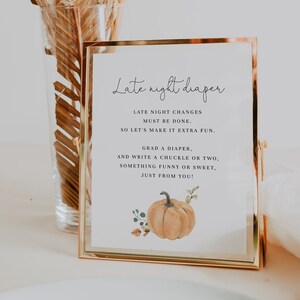 Peut inclure: Un panneau doré avec le texte "Late night diaper" en écriture élégante. Le panneau comprend des instructions pour les changements de couches, avec une illustration de citrouille à l'aquarelle. Un vase en verre transparent avec de l'herbe de la pampa séchée en arrière-plan.