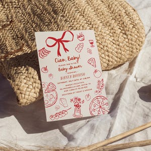May include: A baby shower invitation with red illustrations of food and baby items. The invitation reads "Ciao, Baby!" and includes event details. The invitation is on a white background, with a woven basket in the background.