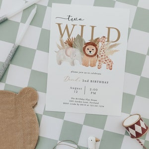 Op de afbeelding: Een witte kaart met een gouden en bruine illustratie van een leeuw, een giraffe en een olifant. De tekst "two WILD" staat in gouden letters. De kaart is een verjaardagsuitnodiging voor David's 2e verjaardag. De uitnodiging bevat de datum, tijd en locatie van het feest.