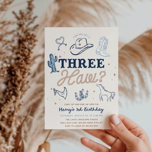 Könnte beinhalten: Eine cremefarbene Einladung mit Cowboy-Thema. Der Text "THREE Haw?" ist in Marineblau und Schriftart im Seil-Stil gehalten, mit Illustrationen eines Cowboyhuts, Stiefeln und eines Kaktus. Die Einladung ist für Henrys 3. Geburtstag, mit Veranstaltungsdetails.