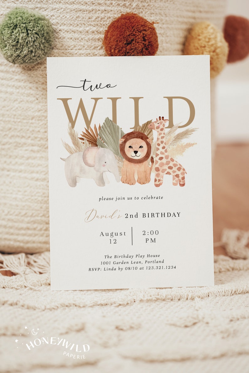 Op de afbeelding: Een witte uitnodigingskaart met gouden letters die een tweede verjaardagsfeestje voor een kind aankondigt. De uitnodiging bevat een aquarel-illustratie van een leeuw, een giraffe en een olifant met tropische planten. De tekst luidt "two WILD David's 2nd BIRTHDAY August 12 2:00 PM The Birthday Play House 1001 Garden Lean, Portland RSVP: Linda by 08/10 at 123.321.1234 HONEYWILD PAPERIE".