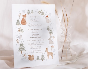 May include: A white invitation card with a Winter Wonderland theme. The card features watercolor illustrations of woodland animals, snowflakes, and pine trees. Text includes "Baby Shower" and event details.
